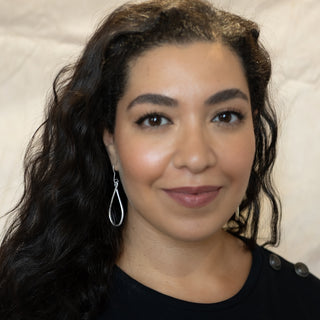 Model wearing Nile & Nova’s Silver Ripple earrings — chunky, reflective silver loops inspired by movement and flow.
