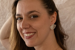 Model smiling in natural light while wearing the Soleil earrings by Nile & Nova, fan-inspired silver design.