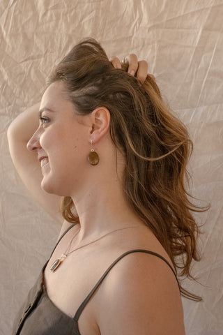Woman wearing Noira sterling silver stone drop earrings and matching pendant necklace, shown in side profile against a soft neutral backdrop.