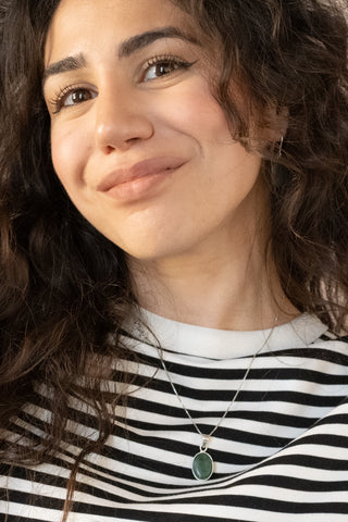 Sterling silver necklace with green oval stone pendant worn by curly haired model in striped top by Nile & Nova