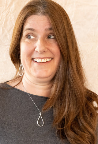 Close-up portrait of model styling the Silver Ripple Necklace with matching silver earrings.