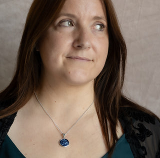 Woman wearing a necklace with a blue pendant against a neutral background