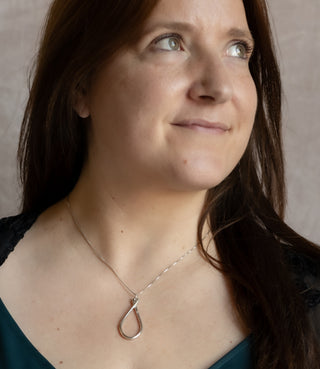 Model wearing the Silver Ripple Necklace with an elegant elongated teardrop pendant on a fine silver chain.