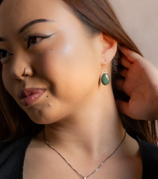 Close-up of a woman wearing a green gemstone earring.