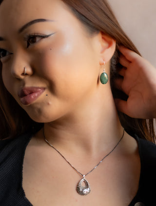 Close-up portrait of model wearing the Lace Drop Necklace with an ornate lace inspired pendant.