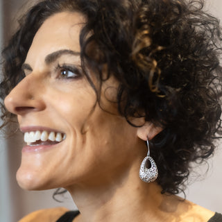 Model smiling in natural light while wearing the Lace Drop earrings in polished sterling silver from Nile & Nova.