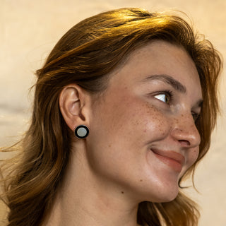 Close-up of model wearing the Monochrome earrings by Nile & Nova — minimalist round studs in black and silver.