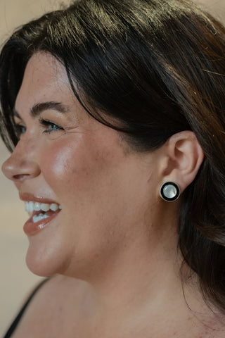 Model laughing in natural light, showcasing Nile & Nova’s Monochrome silver and black circular stud earrings.