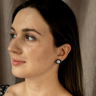 Model wearing Nile & Nova’s Monochrome earrings — modern black-centered silver studs with smooth high-shine finish.