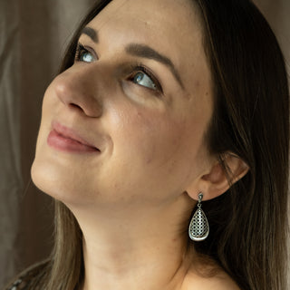 Close-up of model smiling while wearing Nile & Nova’s Mashrabiya earrings with intricate openwork detailing.