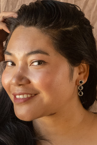 Model wearing Nile & Nova’s Orbit earrings featuring polished silver rings linked in a modern drop style.