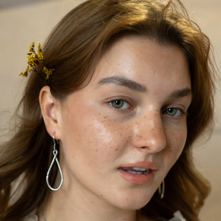 Model wearing the Silver Ripple earrings in polished sterling silver by Nile & Nova, featuring modern sculptural curves.