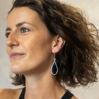 Model wearing the Silver Ripple earrings in polished sterling silver by Nile & Nova, featuring modern sculptural curves.