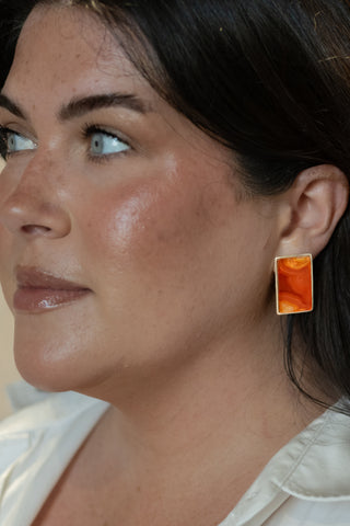 Model wearing Nile & Nova’s Sunset Stone earrings — rectangular silver studs with a radiant amber finish inspired by dusk light.