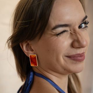 Close-up of model smiling while wearing Nile & Nova’s Sunset Stone earrings — warm-toned silver studs with amber color detail.
