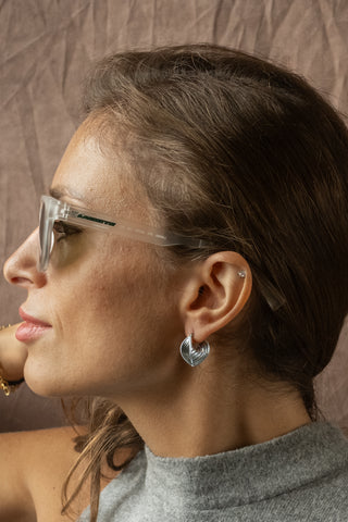 Model in natural light wearing the Tide earrings by Nile & Nova, elegant silver design evoking fluid movement.